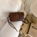 Detail of dark brown leather crossbody bag with silver heart charm on white sofa - No Pendant / Brown