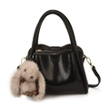 Glänzende schwarze Handtasche mit goldener Hardware und grauem Plüschhasen-Anhänger - Mit Anhänger / Schwarz