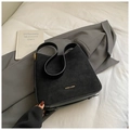 Detail of suede and leather tote bag with gold logo lettering on dark suit background - Black
