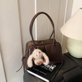 Dark brown leather Boston bag with plush rabbit charm displayed on design books - With Pendant / Brown