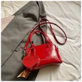 Dettaglio della borsa rossa lucida con ciondolo a cuore e logo goffrato su pelle liscia - Stile con Ciondolo a Cuore / Rosso