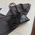 Minimalistische zwarte lakleren shopper met hartjeshanger op een grijze blazer - Zwart