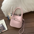 Détail du sac seau en cuir litchi rose avec breloque ours sur parquet en bois - Avec Pendentif / Rose