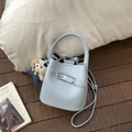 Detail der hellblauen Beuteltasche mit Lychee-Ledertextur und Teddybären-Anhänger - Mit Anhänger / Blau