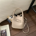 Vue détaillée du sac seau beige à texture litchi avec boucle en métal et bandoulière amovible - Avec Pendentif / Kaki
