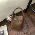 Détail d'un sac seau en cuir grainé marron foncé avec boucle argentée sur sol en bois - Avec Pendentif / Marron