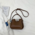 Detail of a brown leather bucket bag with silver twist lock and cute plush bear charm - Brown