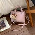 Détail d'un sac bandoulière en cuir rose avec breloque ours sur un sol en bois - Avec Pendentif / Violet