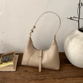 Dettaglio della borsa hobo in pelle albicocca con fibbia metallica su tavolo vintage - Cachi