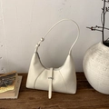 Dettaglio borsa hobo crema su tavolo in legno con cerniera e tracolla regolabile - Bianco