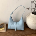 Dettaglio di una borsa Hobo azzurra con fibbia decorativa su un tavolo di legno - Blu
