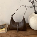 Detail of dark brown dumpling underarm bag on wooden table with vintage props - Brown