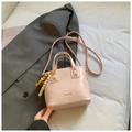 Détail du sac seau en PU rose clair avec breloque perlée et bandoulière sur un blazer gris - Rose