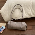 Detalle del bolso cilíndrico color topo con cremalleras plateadas y textura de grano fino - Gris