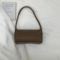 Flat lay of a brown litchi pattern leather baguette bag with metal buckle detail - Brown