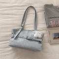 Detail of light blue leather tote bag with white cat plush charm on a textured fabric - Blue