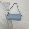 Detail of light blue litchi grain leather texture and adjustable strap buckle on bag - Blue