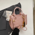 Pink pleated crossbody bag with round handles and beaded tassel accessory in hand - Pink