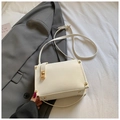Elegant white square crossbody bag with gold hardware on a gray blazer background - Off White