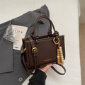 Dark brown pleated crossbody bag with wooden bead charm and knotted handle strap - Brown