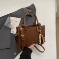 Brown retro leather bucket bag with woven handles and beaded charm accessory - Brown