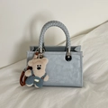 Borsa a tracolla minimalista in pelle azzurra con manico intrecciato e ciondolo orsetto - Blu