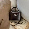 Détail d'un sac boîte vintage marron foncé avec fermoir rotatif argenté sur des livres - Avec Pendentif / Marron