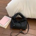 Close-up of black litchi texture PU leather bag with minimalist bow and silver hardware - Black
