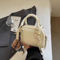 Cremeweiße Handtasche aus Leder in Muschelform mit einem braunen Plüschbärenanhänger - Mit Anhänger / Cremeweiß