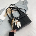 Black leather bucket bag with top handles, crossbody strap, and plush bear charm - Black
