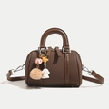 Bolso Boston marrón de tela café con asas de cuero y colgantes decorativos - Marrón
