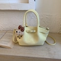 Détail d'un sac seau jaune en cuir texturé avec design plissé et charm de chien en peluche - Jaune avec Pendentif