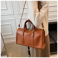 Braune Leder-Boston-Bag mit Goldnieten und Riemen, getragen an der Schulter des Models - Braun