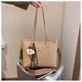 Borsa tote beige in ecopelle con ciondolo a orsetto sopra una valigia argentata - Con Ciondolo / Cachi