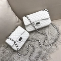 Deux sacs à bandoulière matelassés blancs avec chaîne posés sur un tapis gris - Grand Blanc