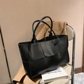 Grande borsa tote nera in pelle intrecciata a quadri larghi su sedia beige - Nero