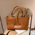 Grande borsa tote in pelle intrecciata marrone caramello scuro su una sedia - Marrone
