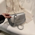 Silver metallic crossbody bag with chunky chain strap over a beige blazer backdrop - Silver