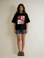 Detailansicht eines schwarzen Oversize-T-Shirts mit Retro-Grafikdruck und Schriftzugmuster - S / Schwarz