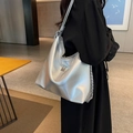 Schicke silberne metallische Hobo-Tasche mit M-Logo und Kettenriemen am Modell - Silber