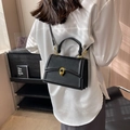 Schicke schwarze Handtasche aus Leder mit goldener Hufeisenschnalle am Model getragen - Schwarz