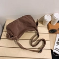 Deep brown canvas crossbody bag with adjustable strap on a wooden table surface - Brown