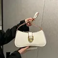Détail du sac blanc porté épaule avec base incurvée et fermoir en fer à cheval doré - Blanc