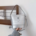 Sac seau argenté avec texture crocodile et boucle en métal tenu par une main - Argent