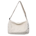 Minimalist beige canvas messenger bag featuring a black adjustable strap and side pockets - White