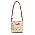 Polka dot canvas tote bag with red bow accent and silver heart charm on white background - Red