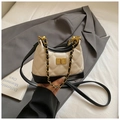 Close-up of quilted suede shoulder bag with gold metal clasp and chain strap detail - White