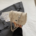 Beige Stepptasche mit Metallkettenriemen und Klappverschluss in Lifestyle-Umgebung - Gebrochenes Weiß