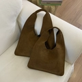 Detail of two dark brown suede tote bags in large and small sizes on a white sofa - Large / Brown