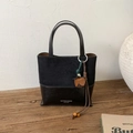Detail of dual-texture black leather tote bag with matte finish and brand logo - Black with Pendant